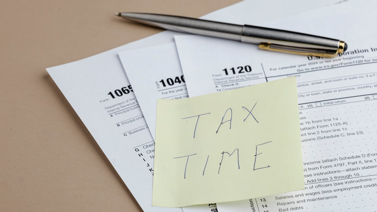 Tax forms with a post-it note on them that says, 