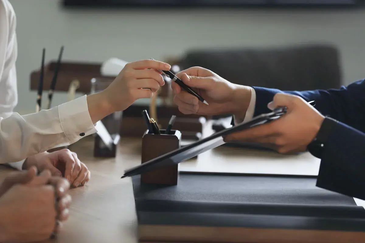 Man-holding-a-document-and-giving-a-pen-to-another-person.jpg