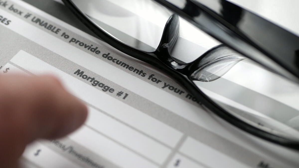A close-up of a mortgage document with eyeglasses sitting on top