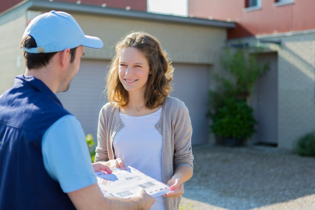 A woman hands an envelope to a delivery person