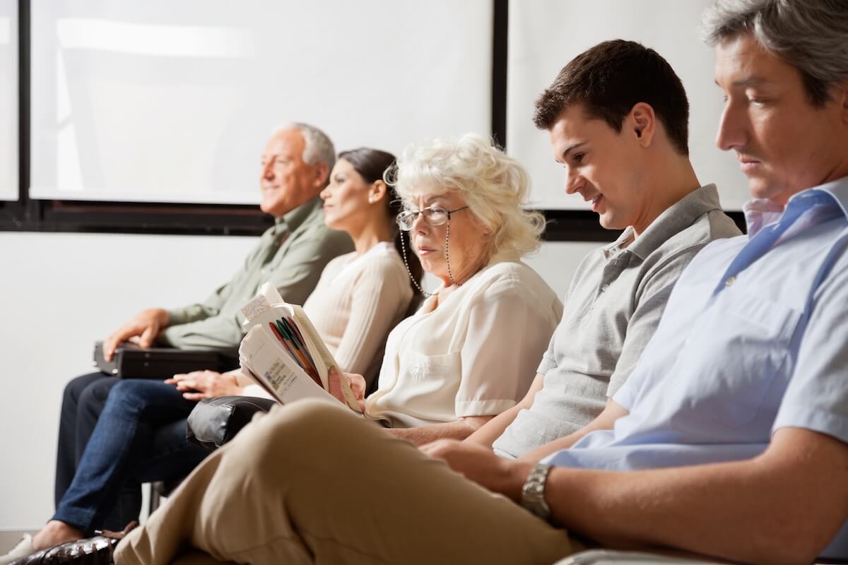 A group of people sit in chairs in a waiting room