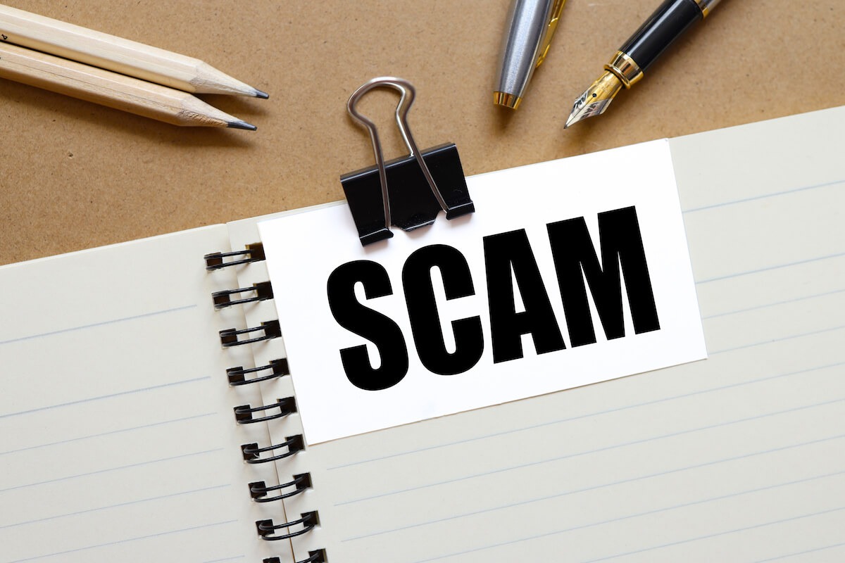 Timeshare scams: The word "scam" is printed on a card and attached to a notebook