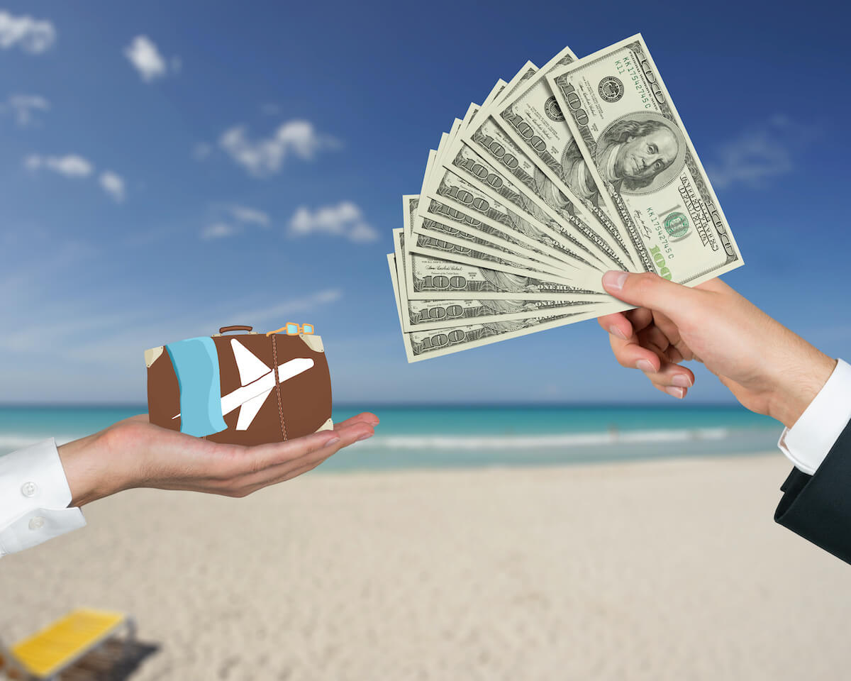 what is a timeshare: hands holding cash and mini suitcase by the beach
