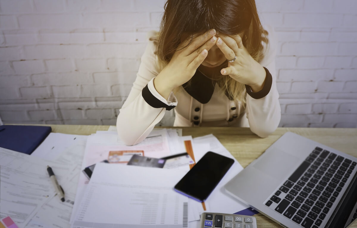 timeshare maintenance fees: stressed woman looking at a pile of paperwork