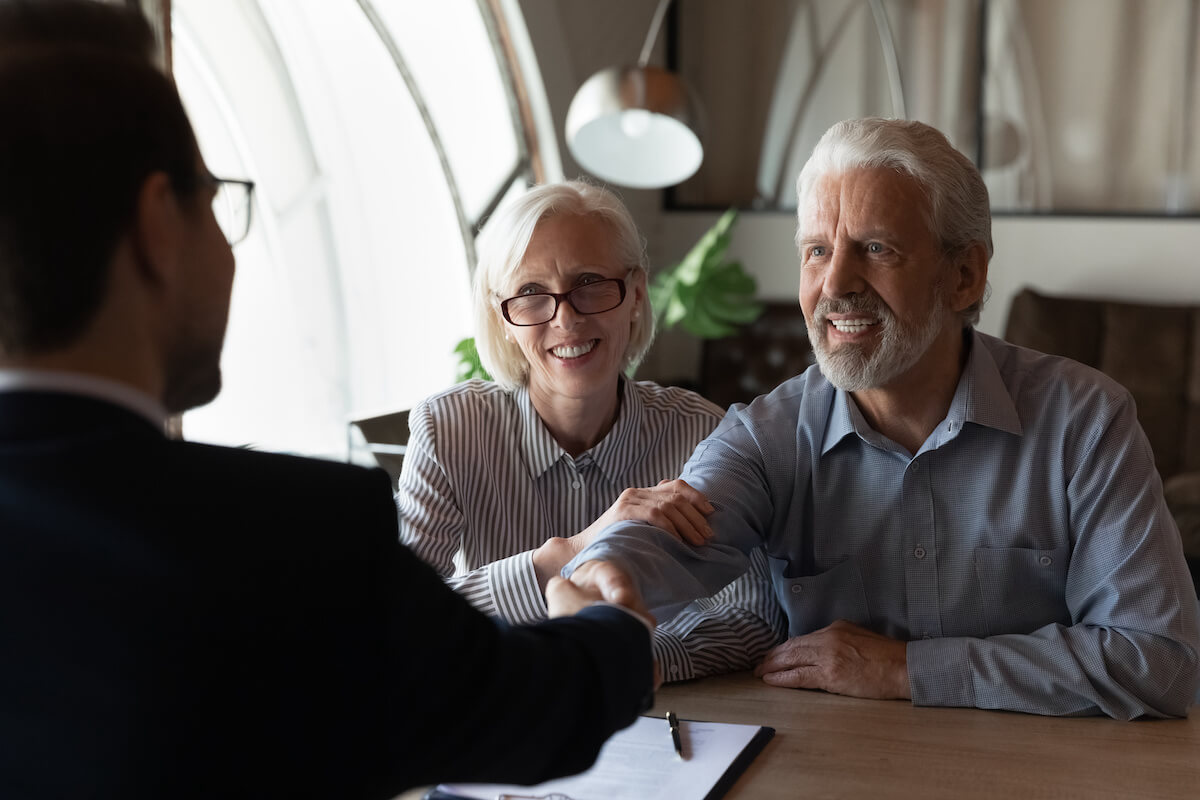 Happy elderly couple shaking hands with an agent