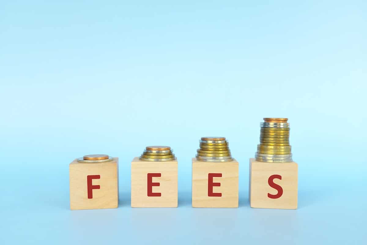 FEES spelled using wooden blocks that have coins on top