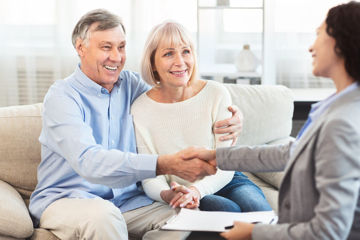 Elderly couple shaking hands with an agent