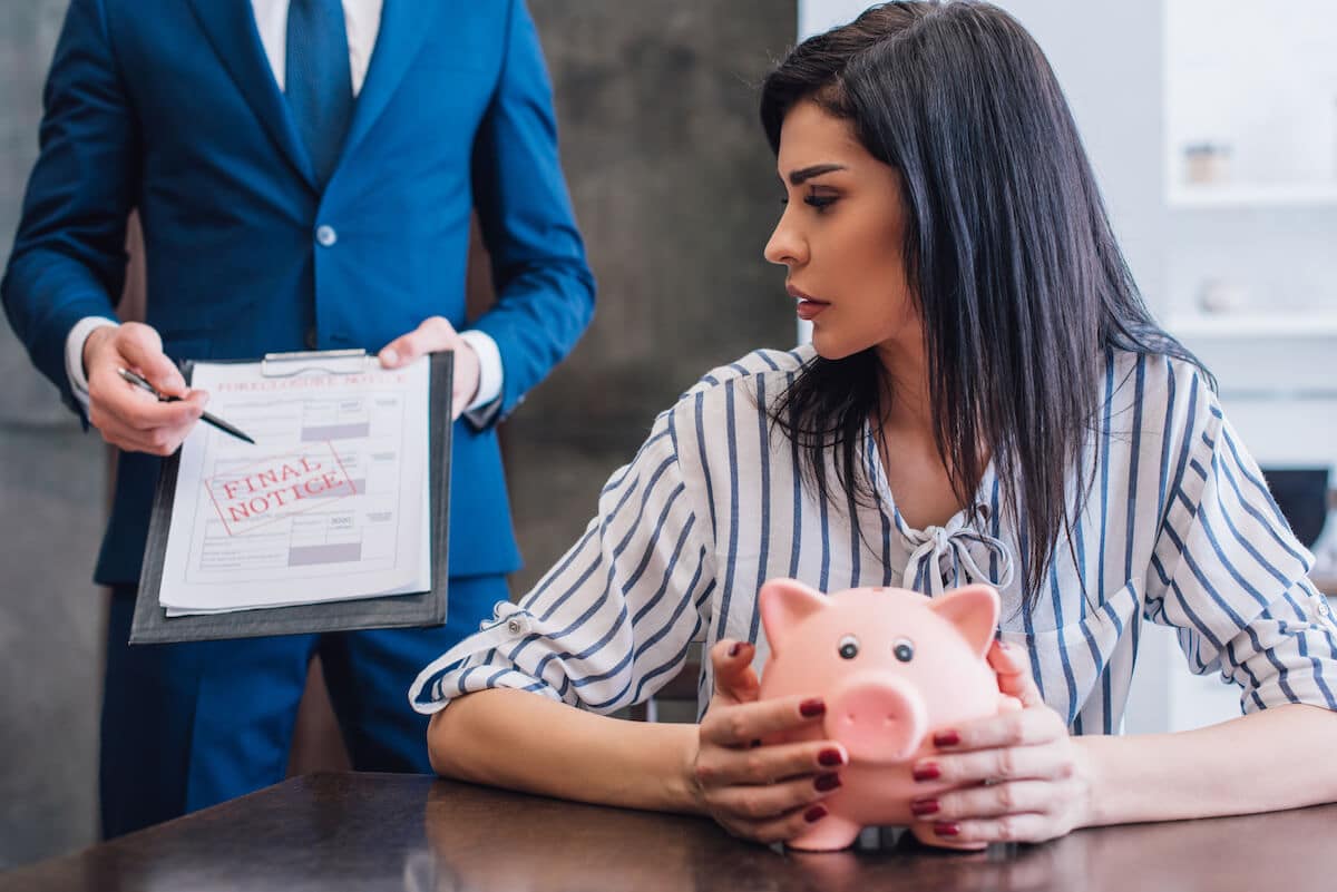 New debt collection laws 2021: woman holding a piggy bank while being served a final notice