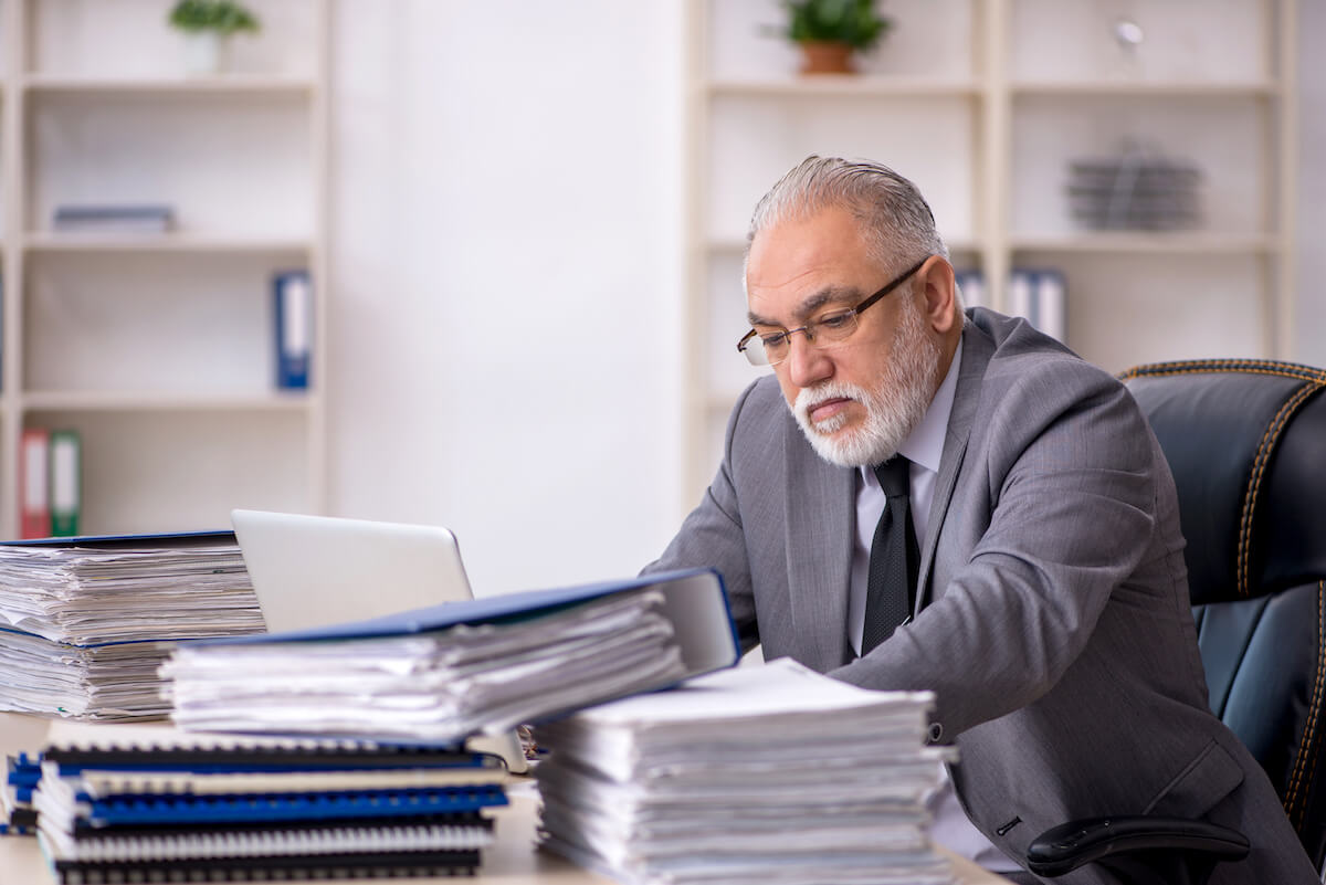 Timeshare exit companies: old employee with stacks of documents on his desk