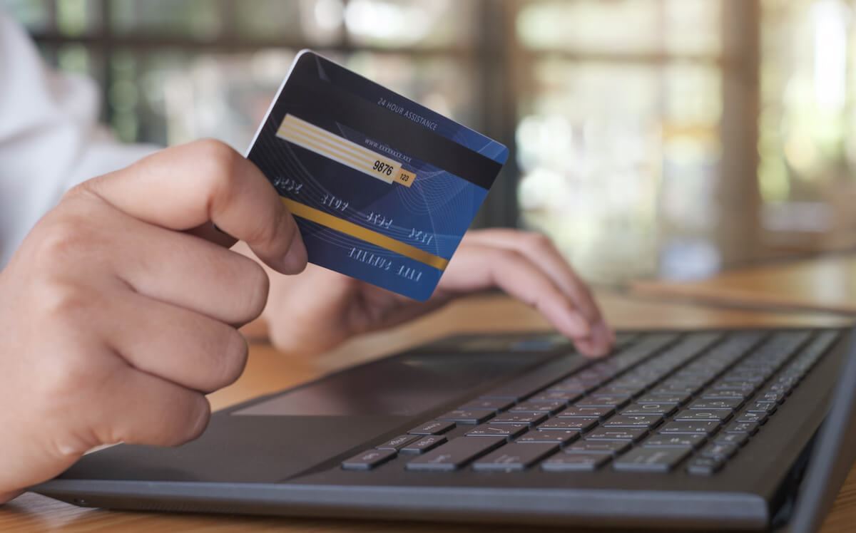 Person holding a credit card and using a laptop