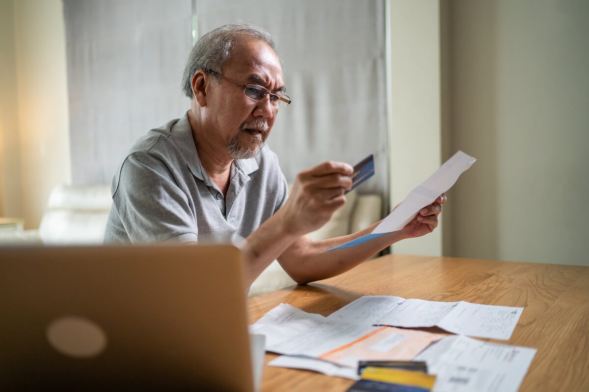 Senior man holding a credit card and a document