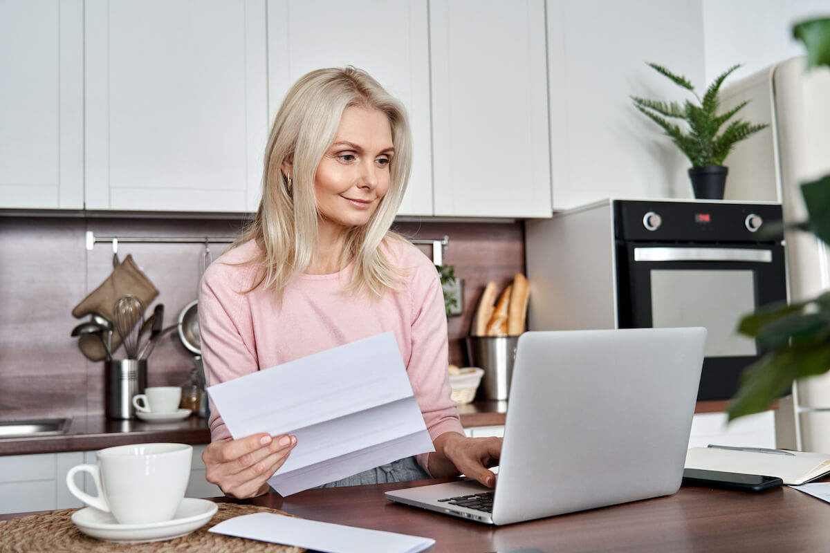 BBB complaints vs reviews: woman using a laptop and holding a document at home
