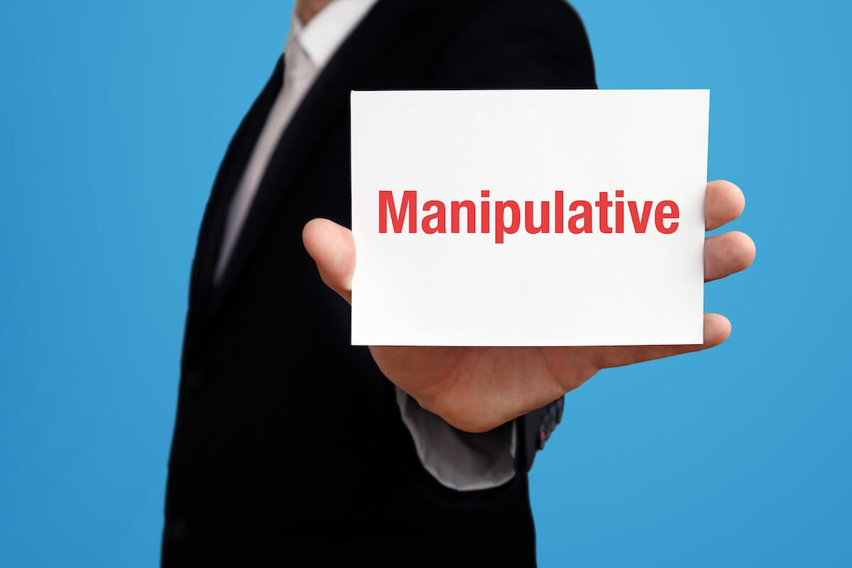Entrepreneur showing a card with the word MANIPULATIVE printed on it