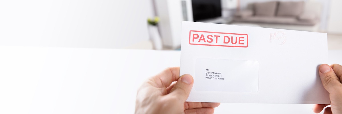 Person holding an envelope with PAST DUE stamped on it