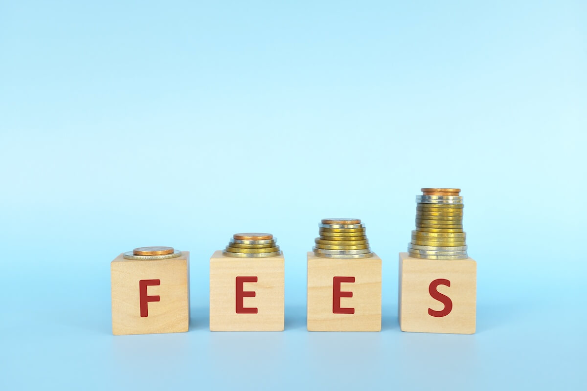 FEES spelled using wooden blocks with coins on top