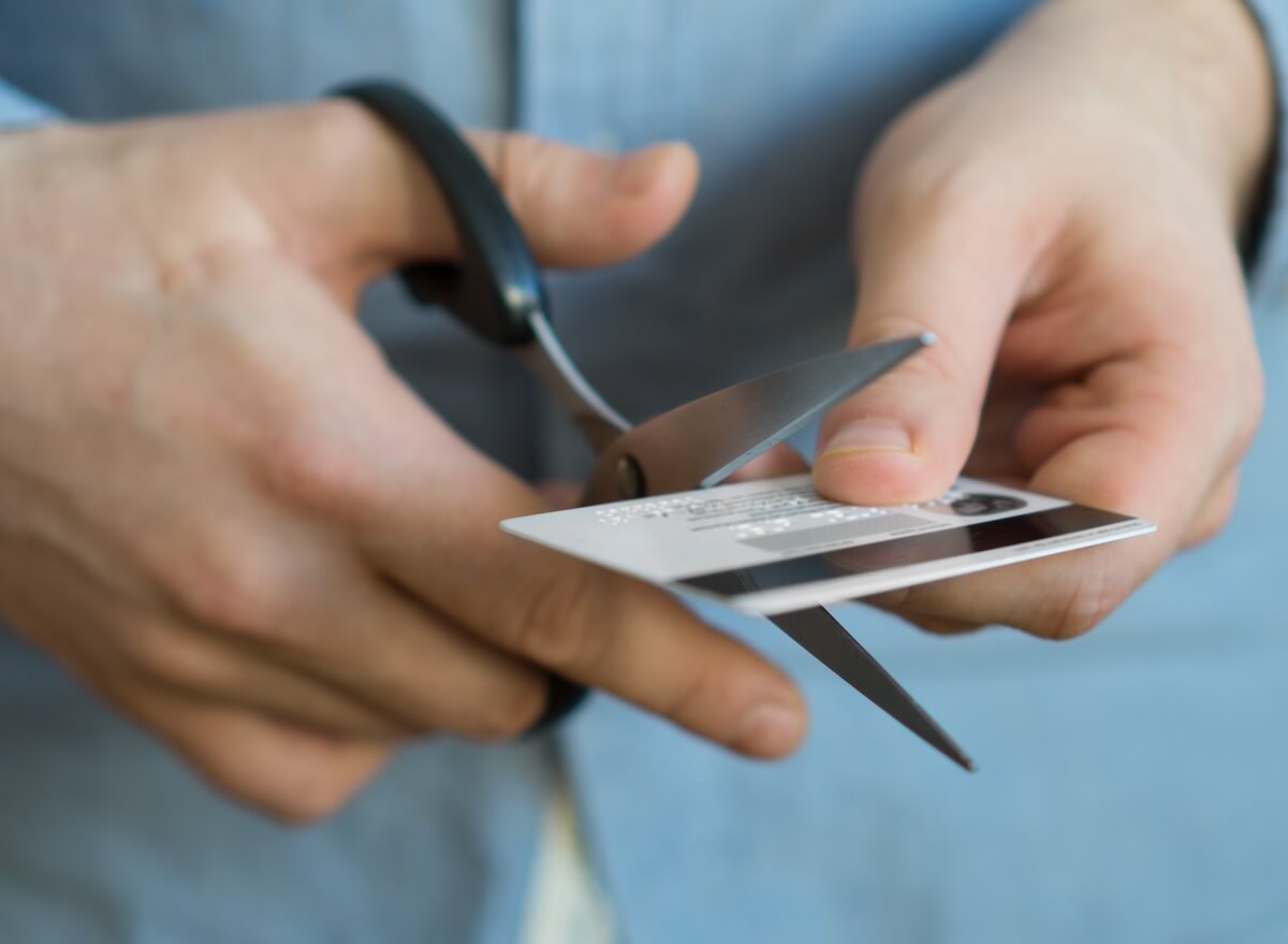 Person cutting a credit card using a pair of scissors