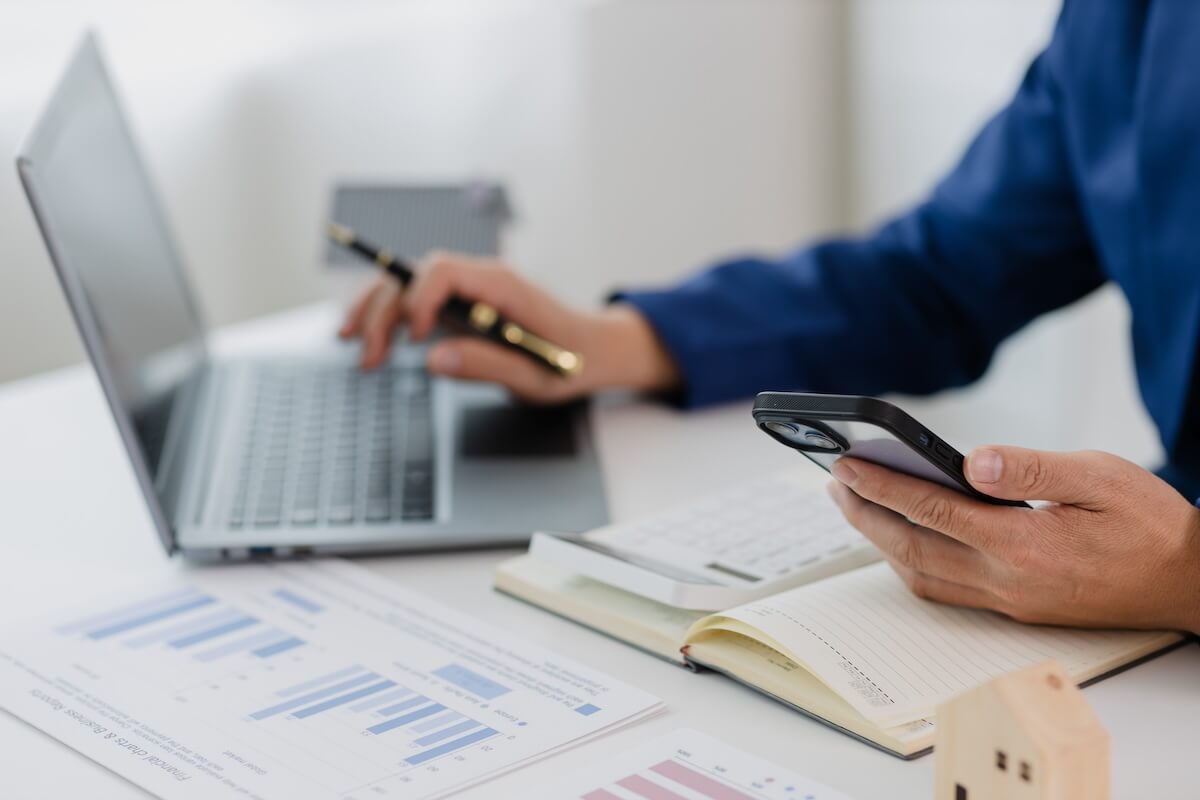 Entrepreneur using a laptop while holding a phone