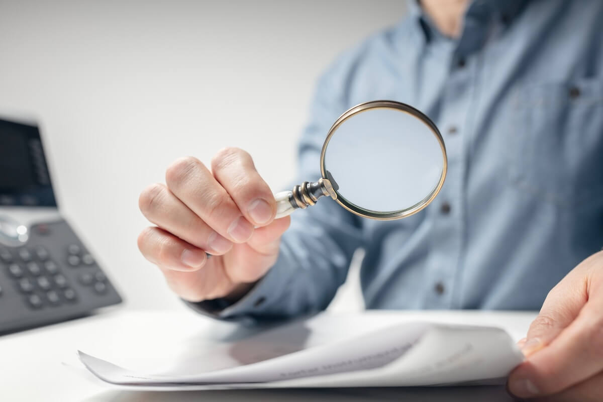 Person using a magnifying glass to read a document