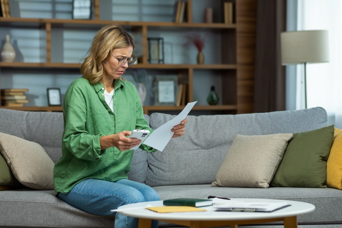 Woman holding her phone while reading a document