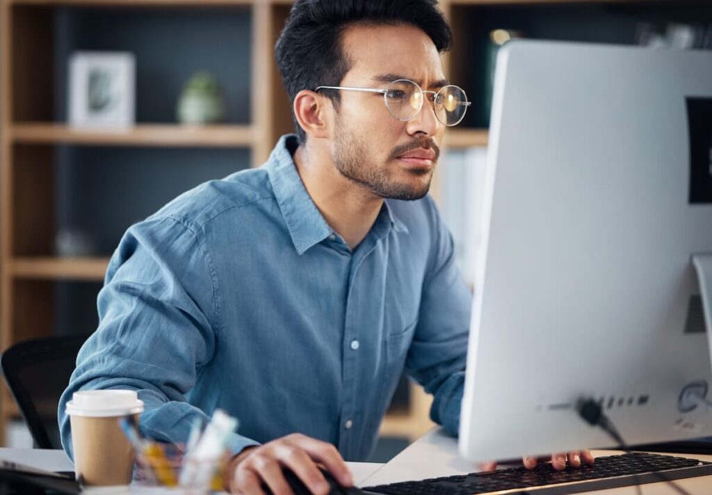 Timeshare cancellation industry: serious man wearing a pair of eyeglasses while using a computer