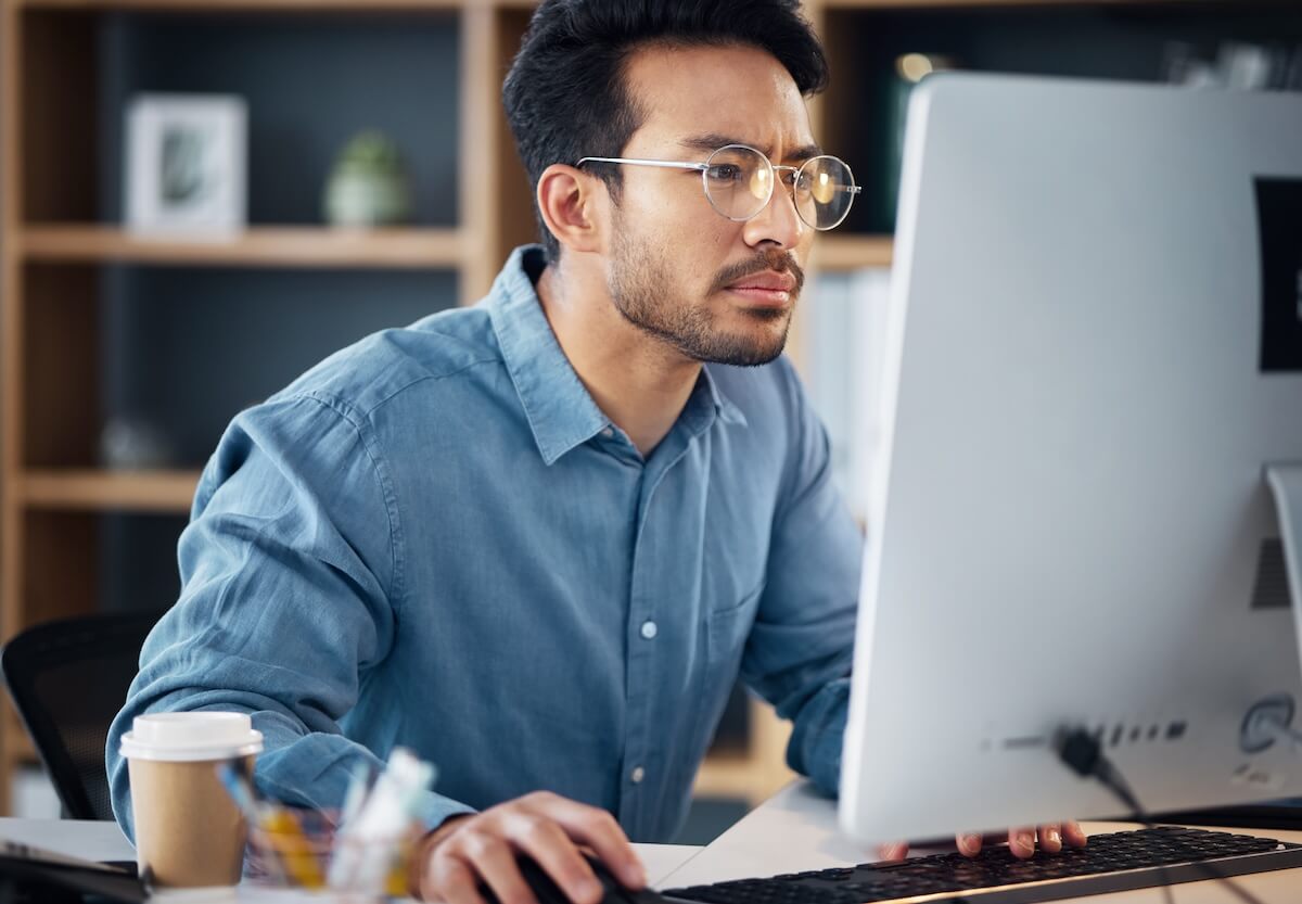 Timeshare cancellation industry: serious man wearing a pair of eyeglasses while using a computer