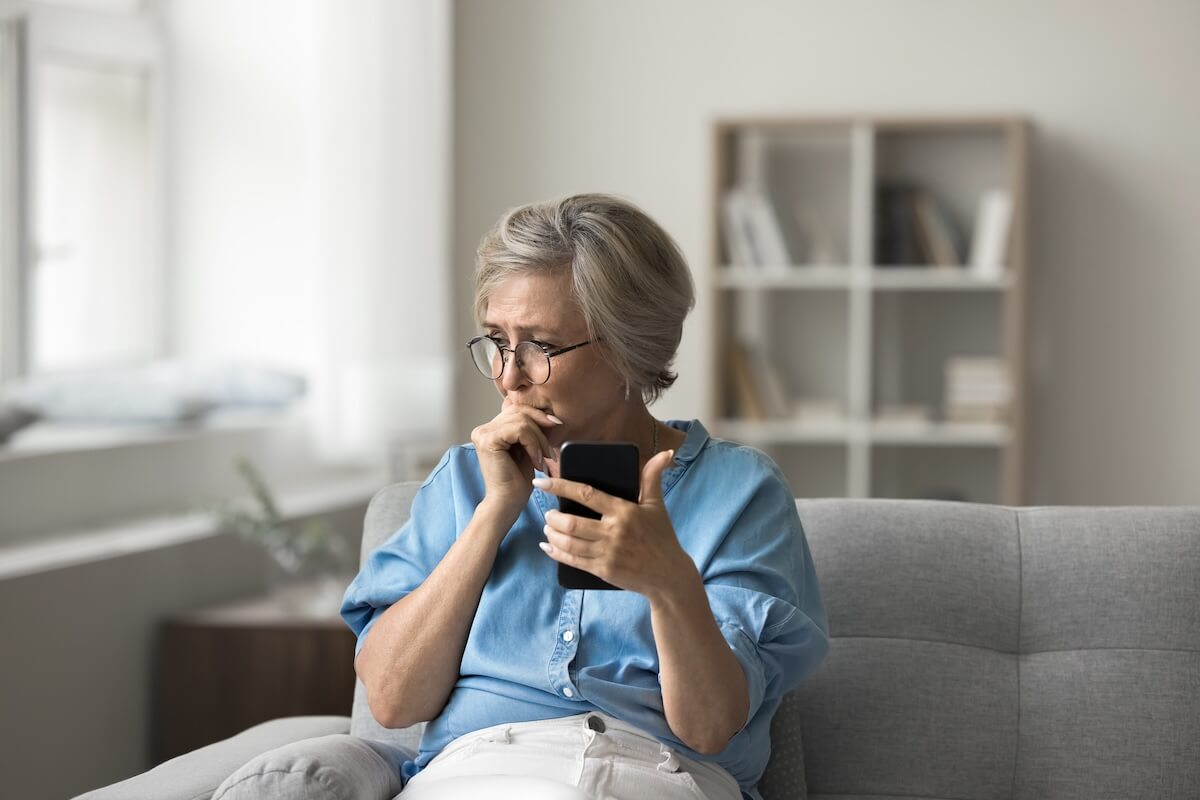 Stressed senior woman holding her phone