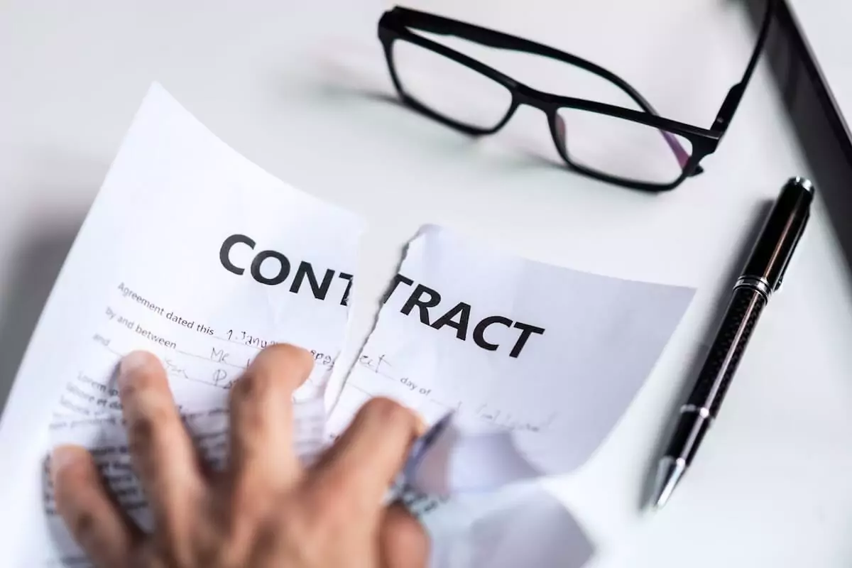 A closeup of a hand crumpling a ripped up contract