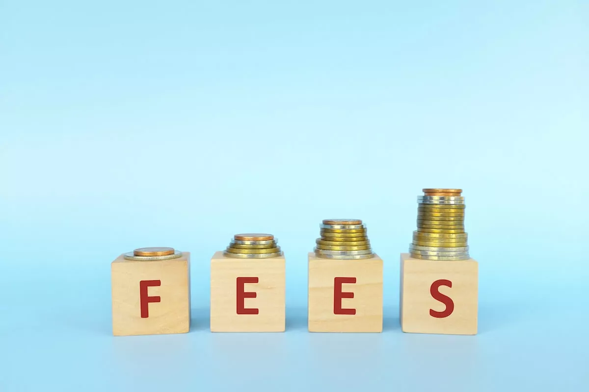 FEES spelled using wooden blocks with coins on top